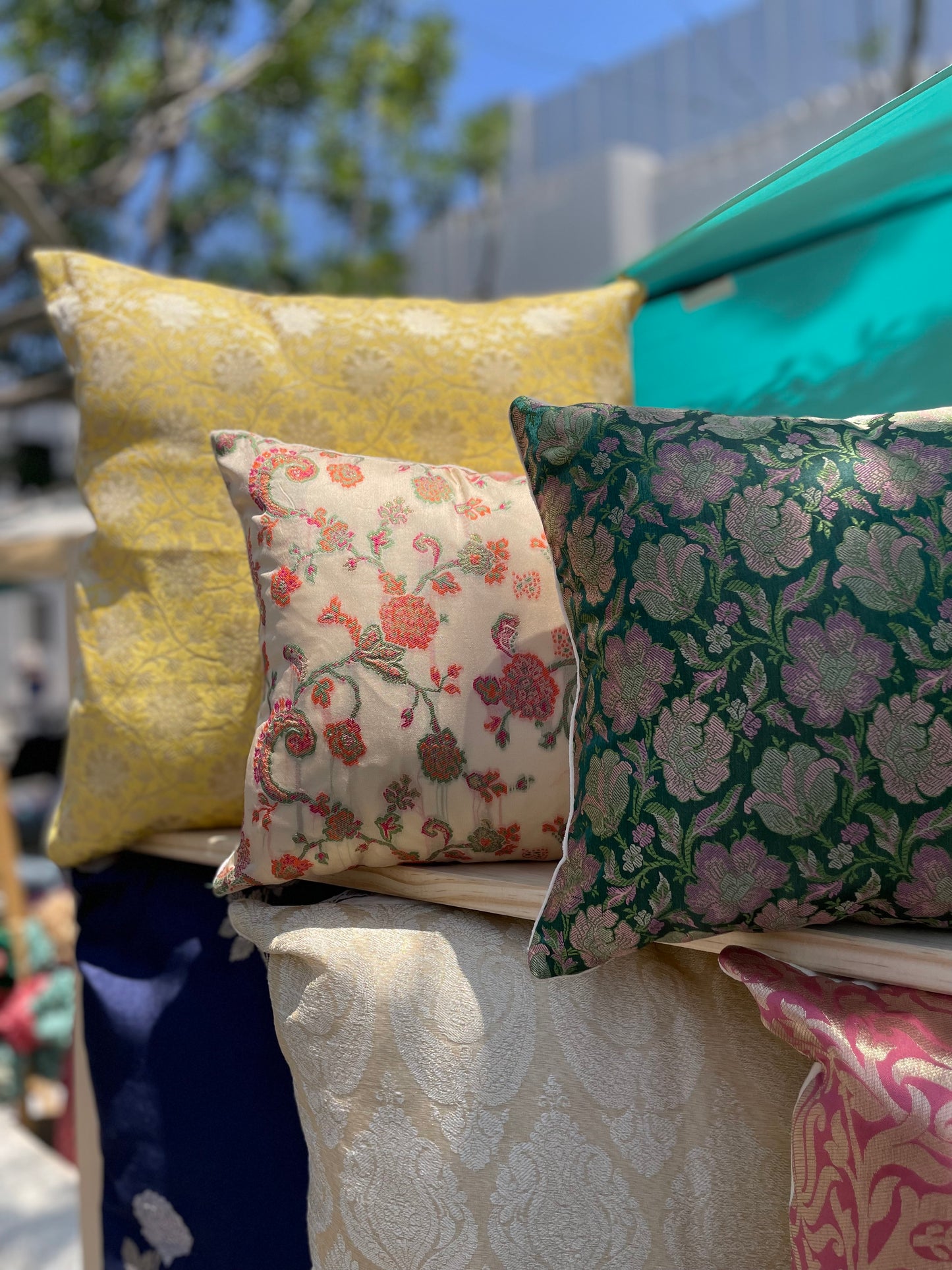 Decorative pillows with floral patterns on a furniture piece outdoors.